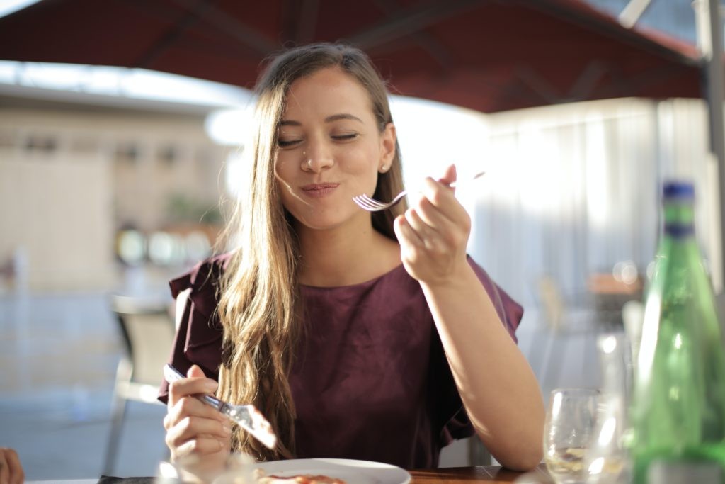 Woman enjoying a meal outdoors while traveling solo, highlighting culinary experiences