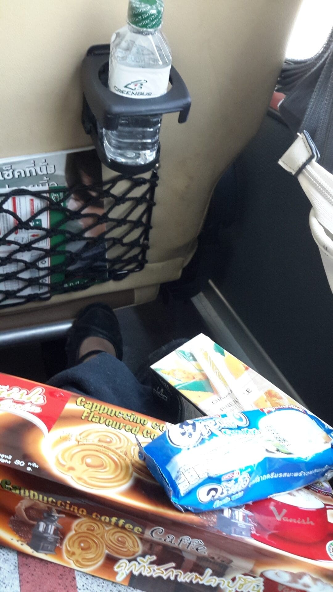 Inside a Greenbus in Thailand showing snacks and a bottle of water.