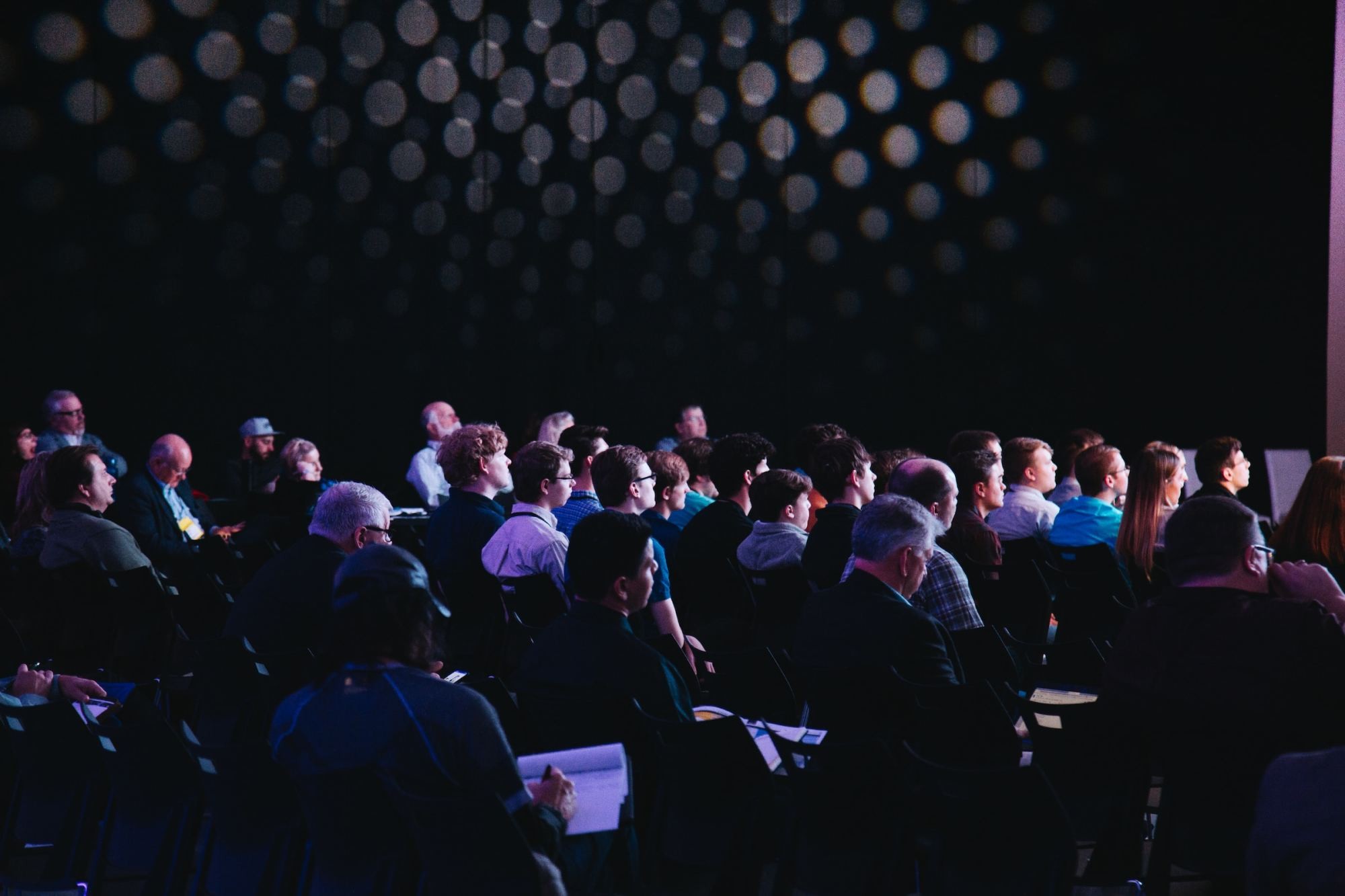 A diverse group of professionals attentively taking notes during a corporate seminar