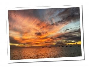 Vibrant orange sunset over a tranquil Caribbean sea, capturing a serene and peaceful atmosphere