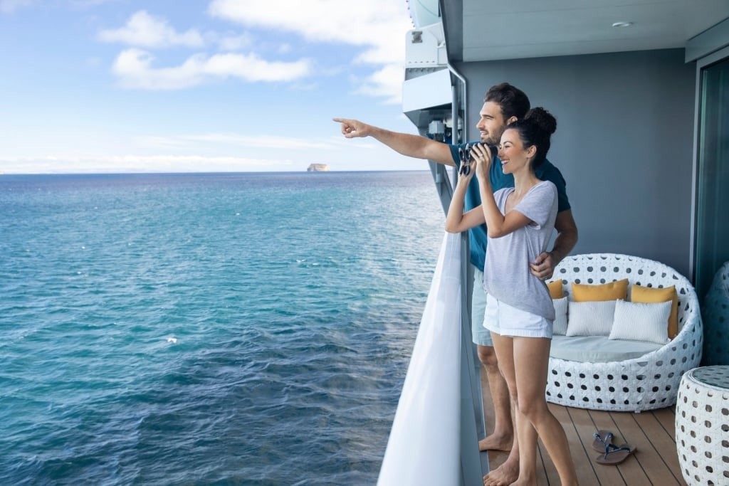 Couple enjoying fresh air and ocean views from a cruise ship veranda, a natural way to combat cruise travel sickness.