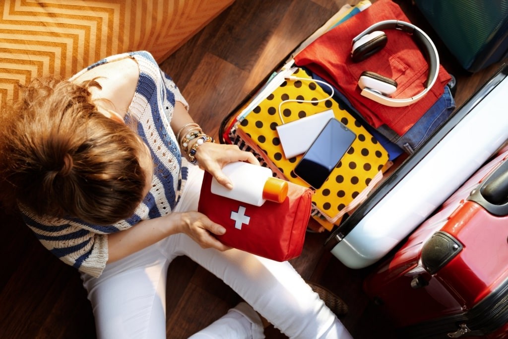 Woman packing seasickness medication and a first aid kit for a cruise to prevent cruise travel sickness.