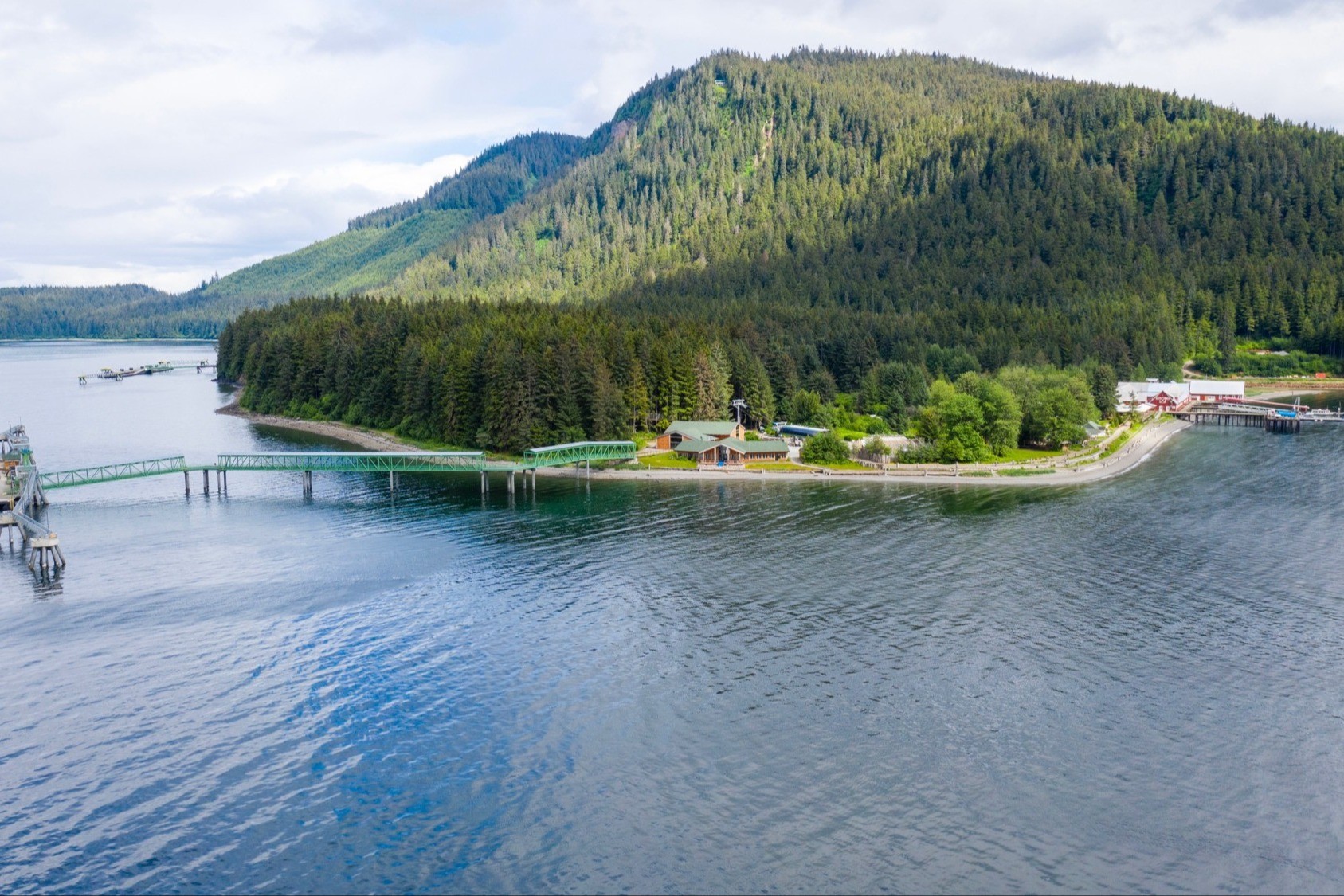 Two cruise ships docked at a scenic harbor surrounded by mountains, showcasing the Alaskan wilderness.