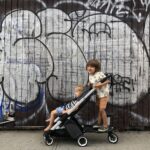 Two kids sitting in a Bugaboo Ant stroller, showcasing its compact size