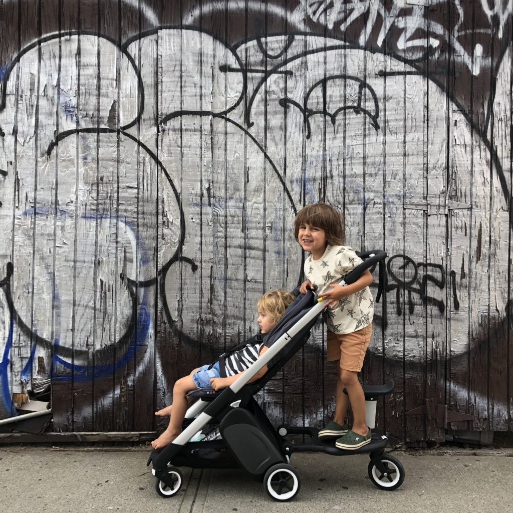 Two kids sitting in a Bugaboo Ant stroller, showcasing its compact size