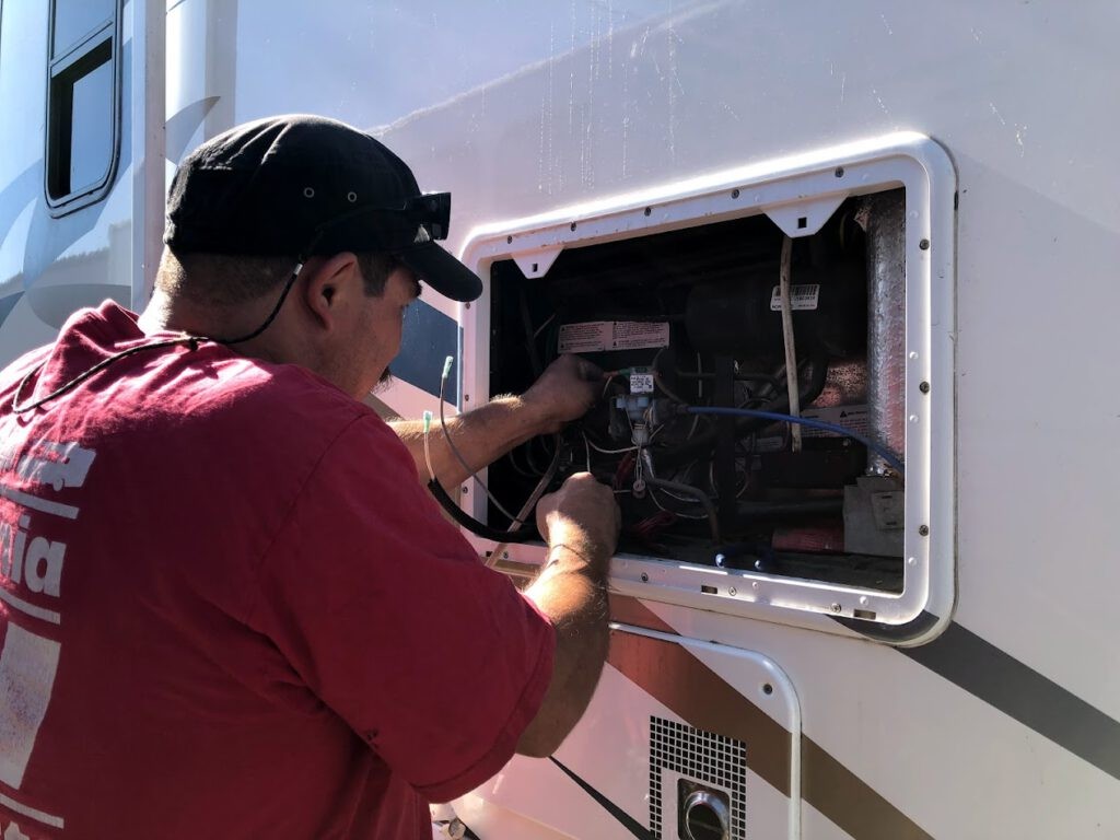 Technicus onderhoudt caravan koelkast, illustreert professionele reparatie.