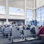 Parents navigating airport security with a baby in a carrier and a stroller, highlighting a stress-free travel experience thanks to preparation.