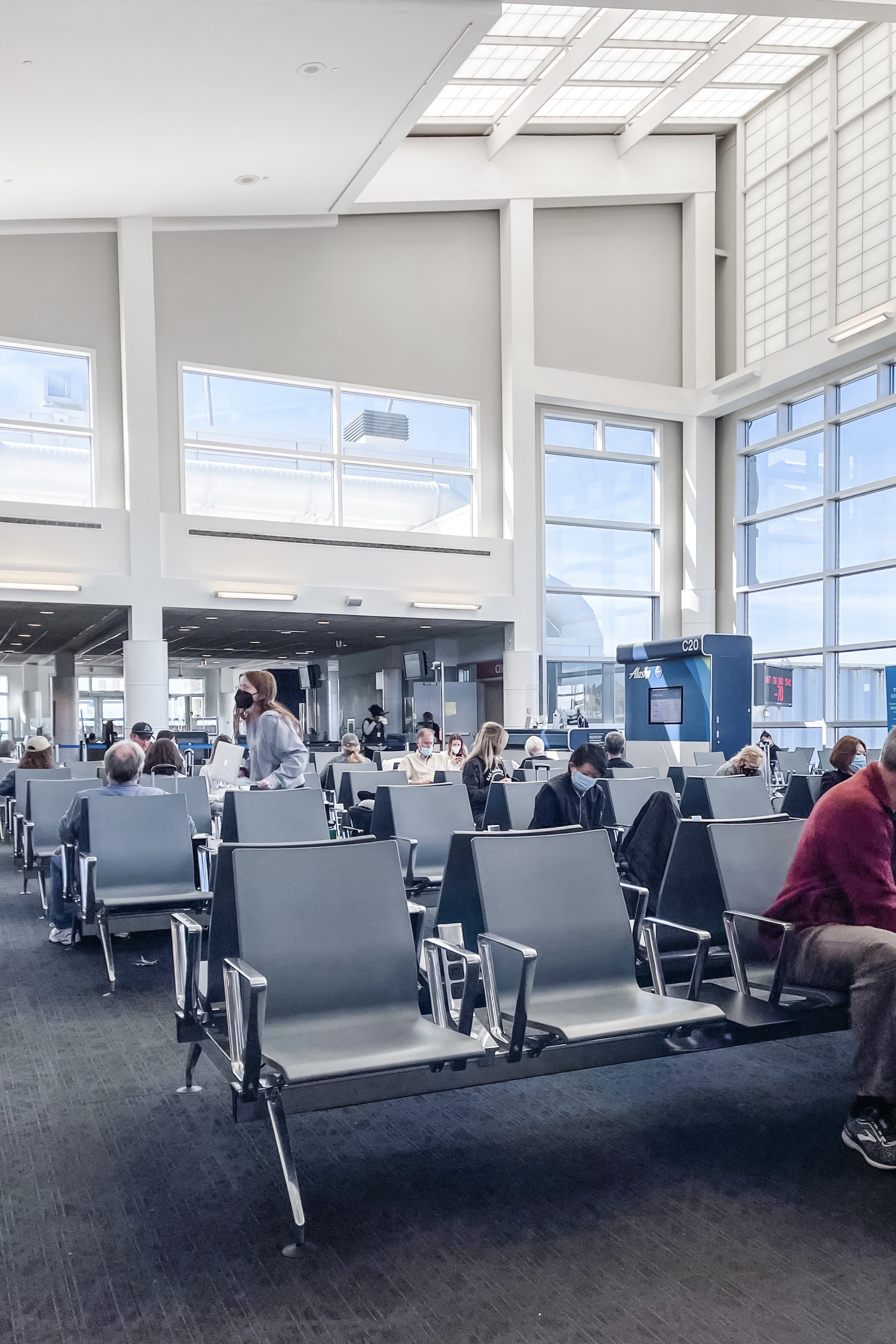 Parents navigating airport security with a baby in a carrier and a stroller, highlighting a stress-free travel experience thanks to preparation.