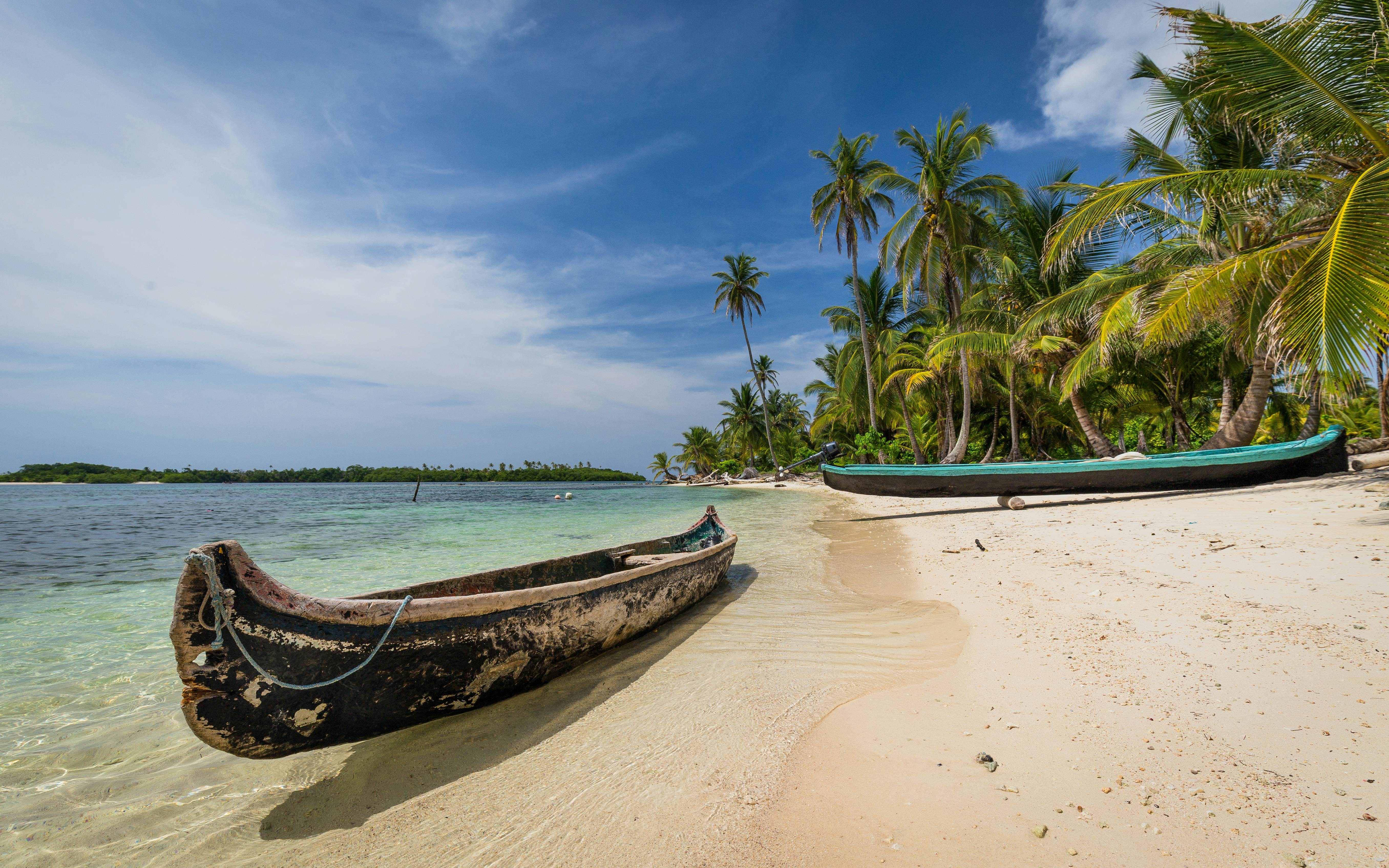 Indigenous canoes on a secluded beach in the San Blas Islands, Panama, portraying a tranquil beach escape during ideal weather conditions.