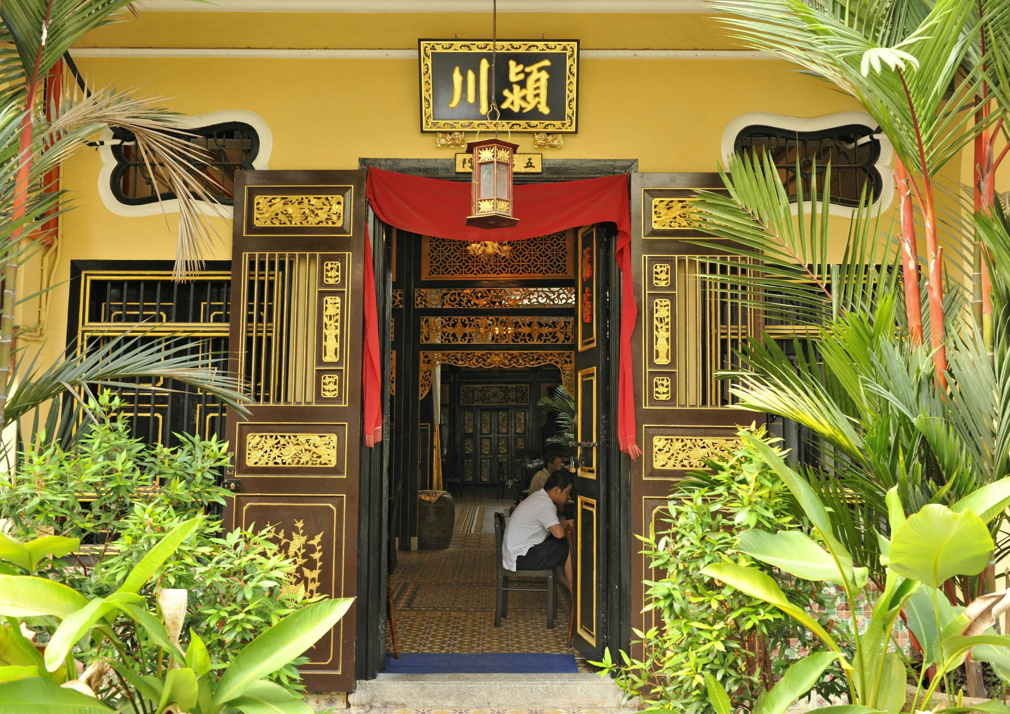 Penang, Malaysia, showcases ornate doorways leading to coffee shops, reflecting the cultural and culinary richness of Georgetown