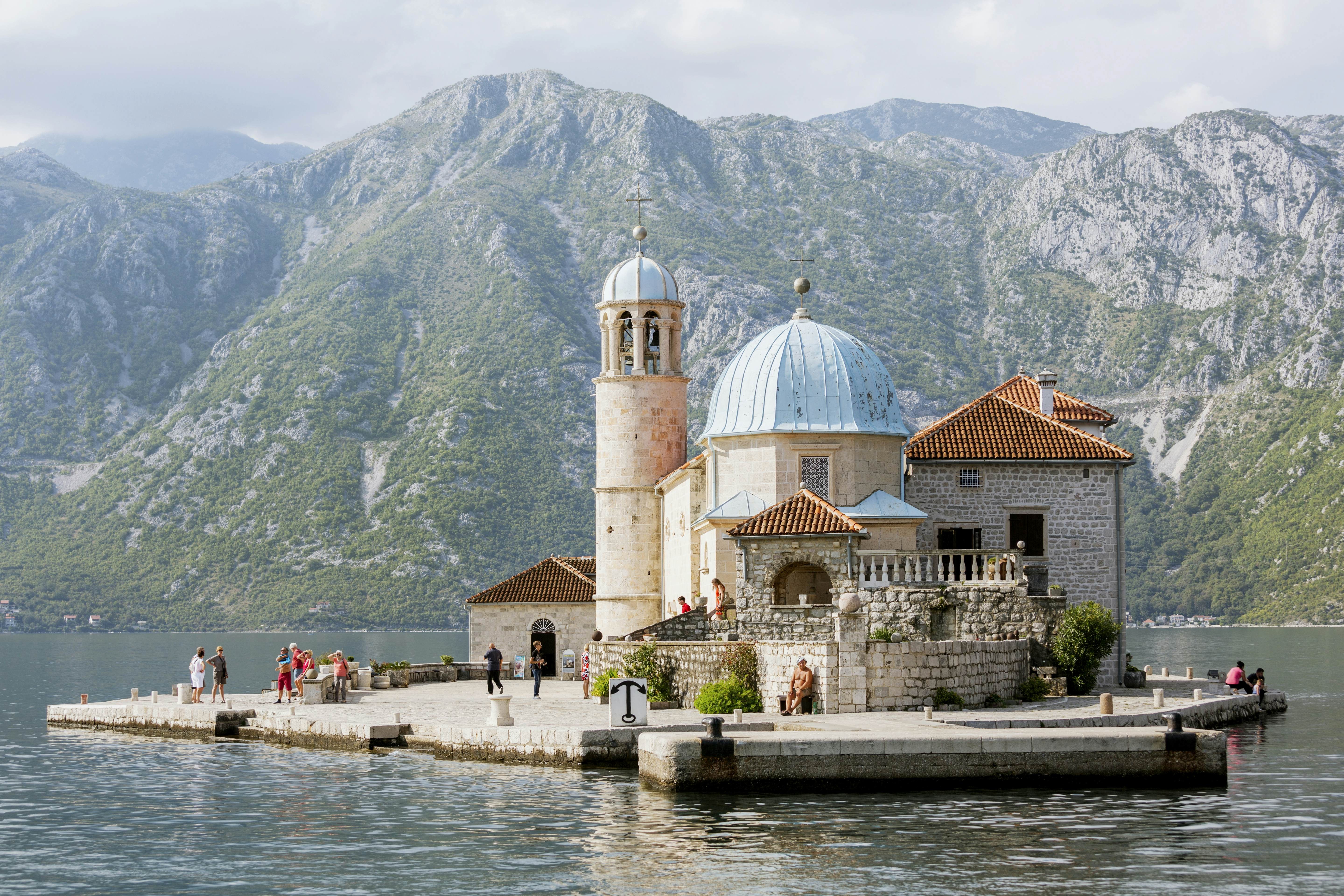 An ornate church sits on a small island with mountains in the background in Montenegro.