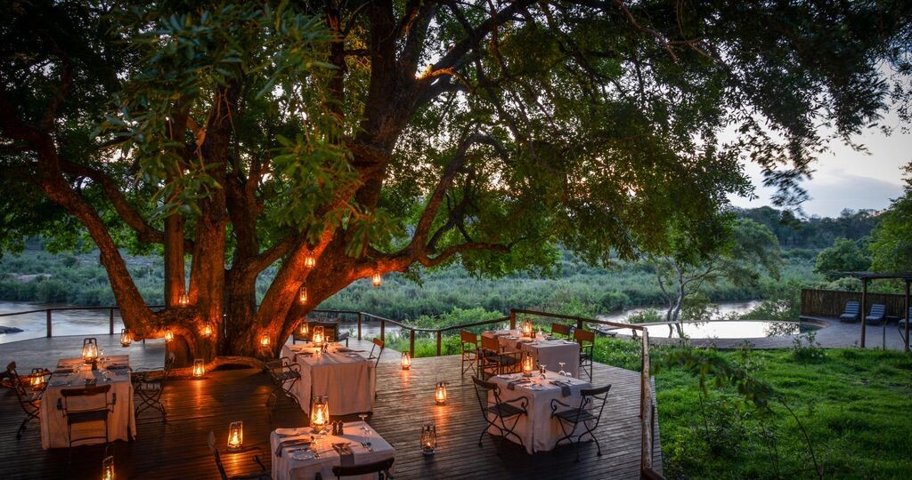 Luxurious outdoor dining deck at Lion Sands Lodge, Kruger National Park, South Africa, suggesting a wildlife safari and luxurious stay for an anniversary