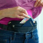 A woman wearing a money belt and pulling out her euros and passport.