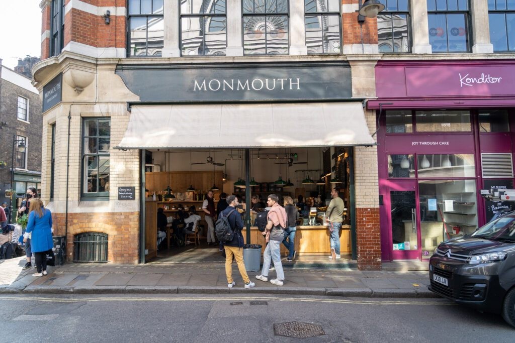 Monmouth Coffee shop exterior in Borough Market, London, with people queuing outside