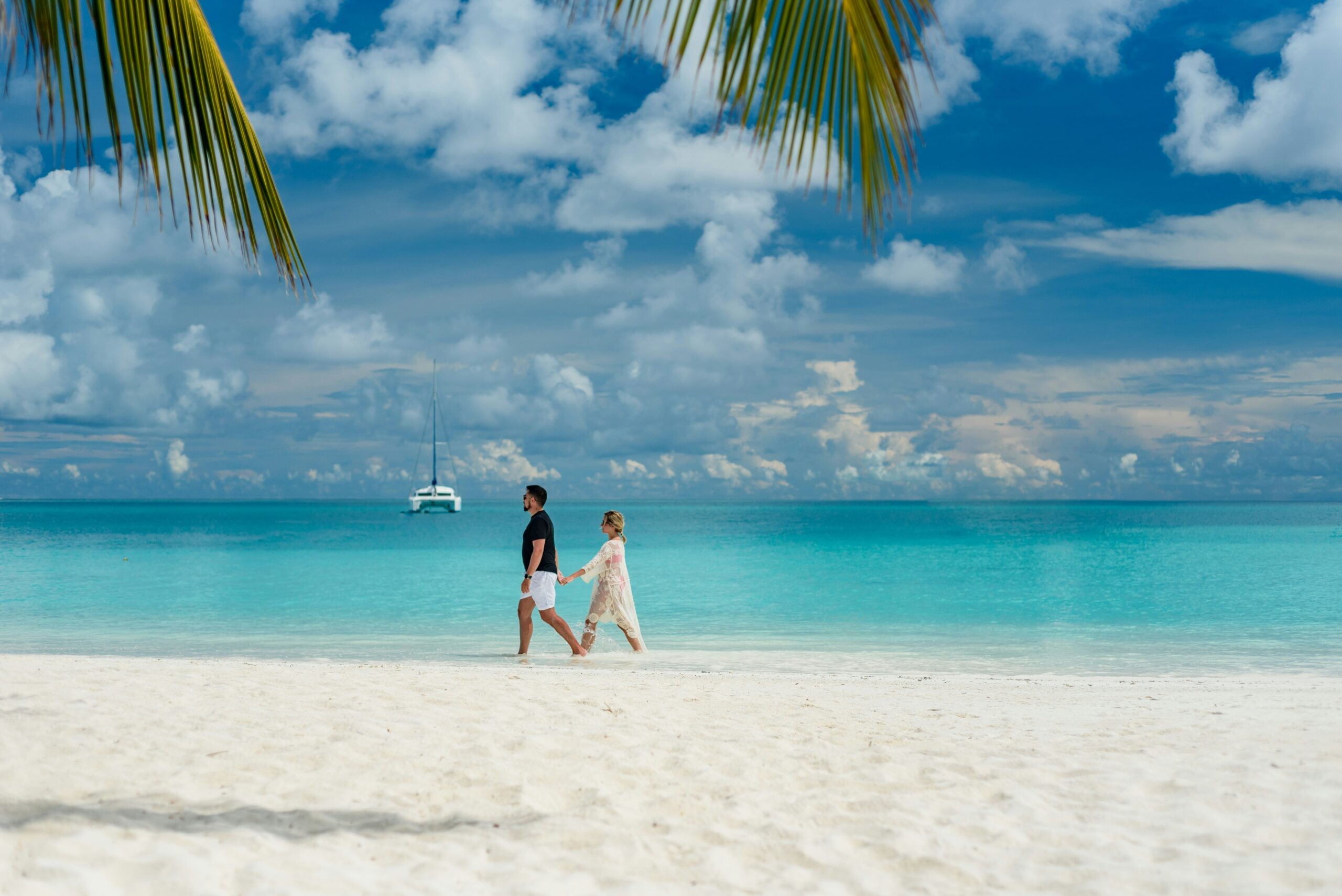 Couple walking hand-in-hand on a pristine white sand beach in the Maldives, embodying romantic seclusion and luxury