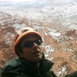 Climber wearing REI Edgewood Travel Coat ascending near the summit of Titan in Fisher Towers