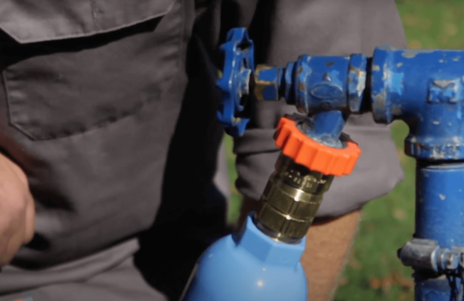 Close-up of a hand pointing to the city water inlet on a travel trailer, emphasizing the necessity of a water pressure regulator for safe connection