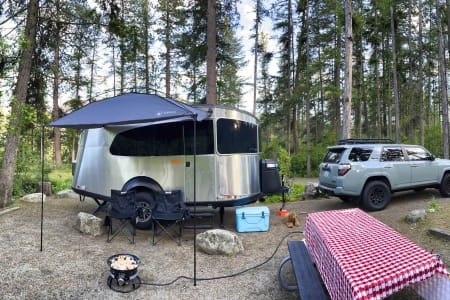 A modern Airstream Base Camp travel trailer parked in a scenic outdoor setting, emphasizing its adventurous and stylish design.