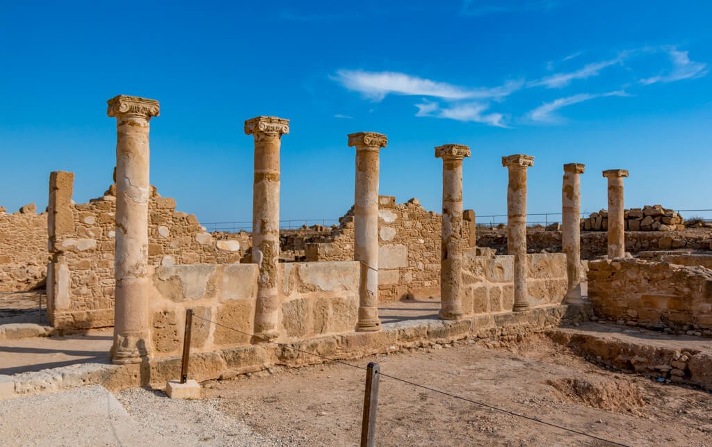 Ancient Roman columns stand tall against a bright blue sky in Paphos Archaeological Park, Cyprus, highlighting its historical significance and status as one of the hottest places in Europe in November.