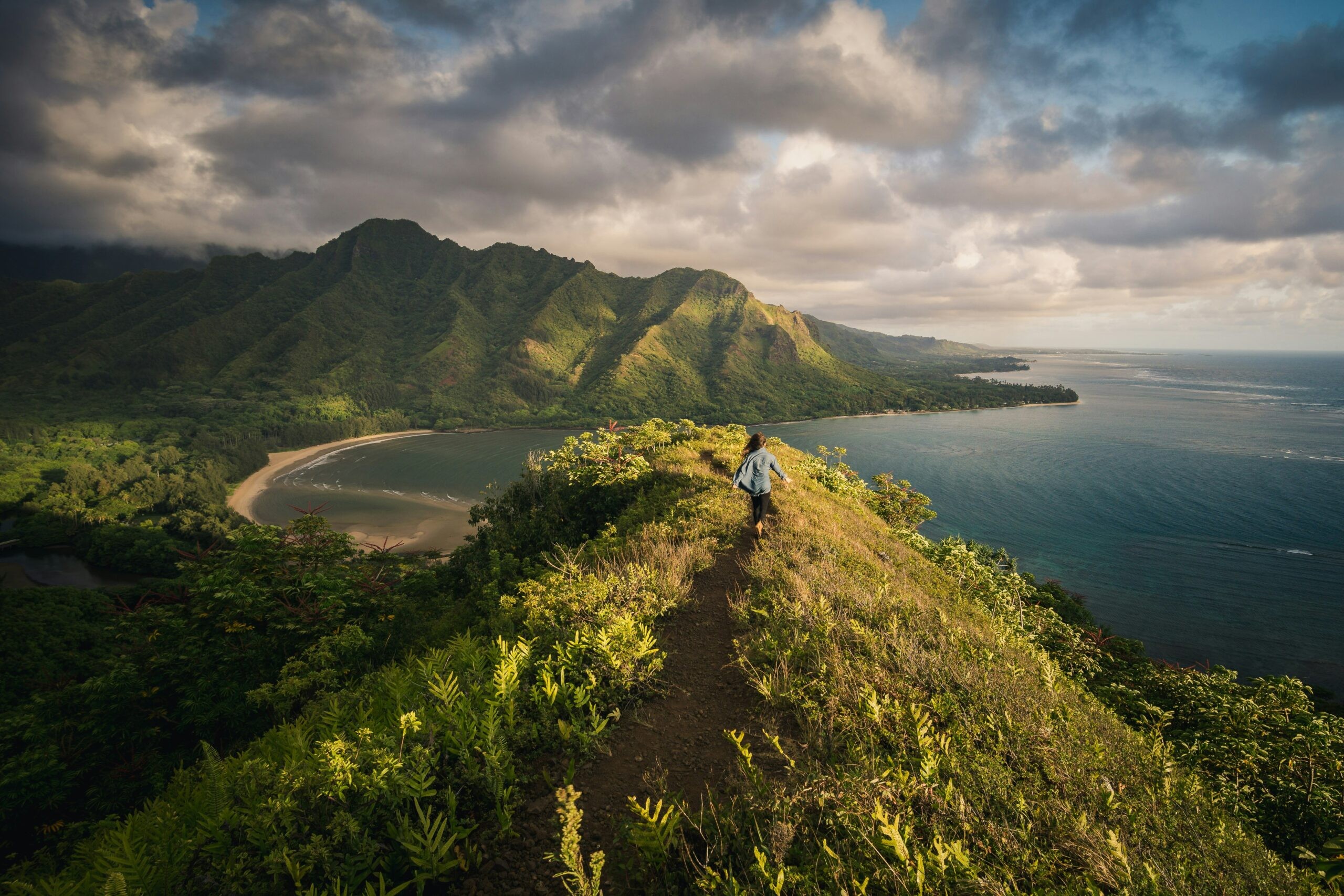 Panoramic view from a lush Hawaiian mountain overlooking the ocean, suggesting diverse landscapes for an adventurous anniversary trip