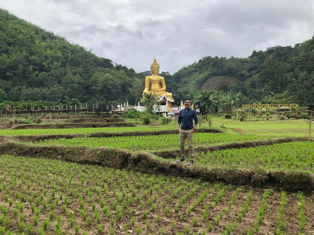 Dan near a Buddha image amidst a Phrae rice field.