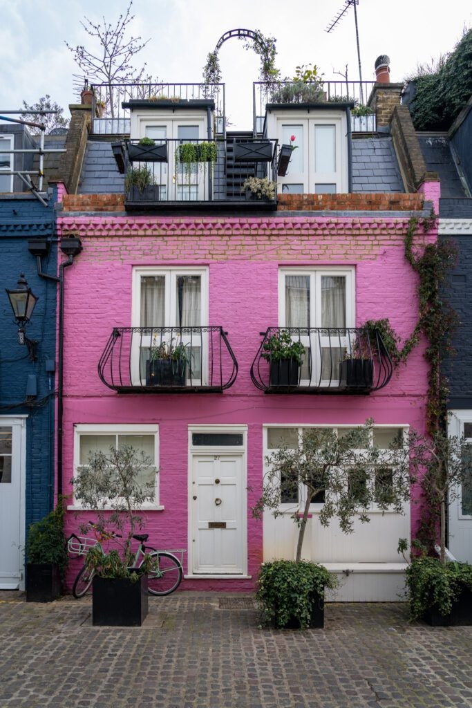 A row of brightly colored terraced houses in Notting Hill, London, showcasing pink, blue, and yellow facades