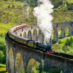 A steam trains rounds a bend on the iconic Glenfinnan Railway Viaduct in Scotland, UK