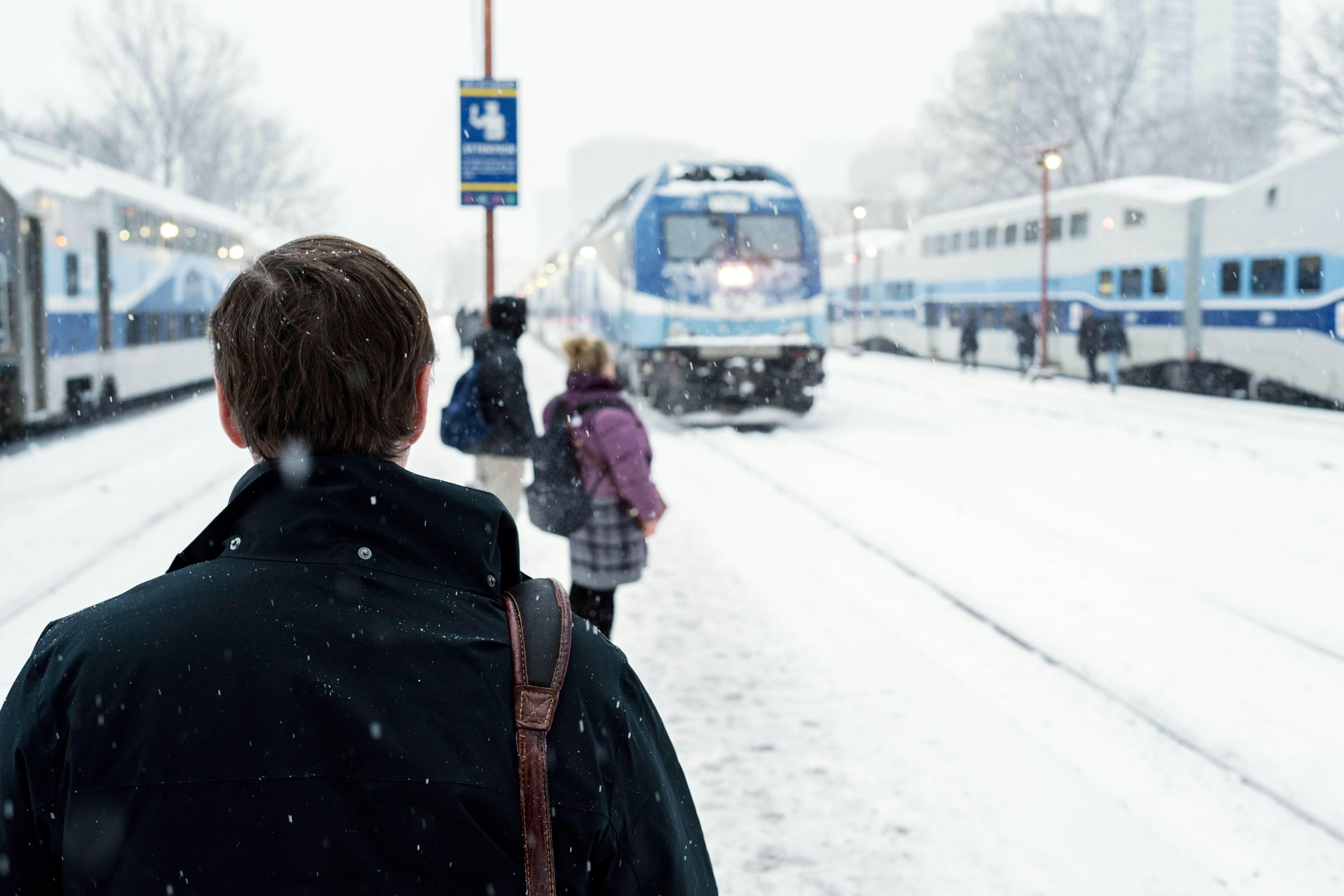 A group of commuters are patiently waiting in the snow for the arrival of an Exo commuter train at Lucien L’Allier station in Montréal, Québec, Canada.