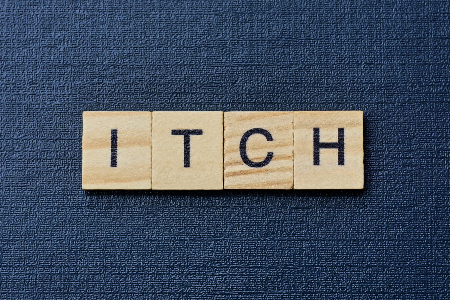 Scrabble tiles reading Itch against a dark blue background - Zap It mosquito bite zapper review for effective itch relief