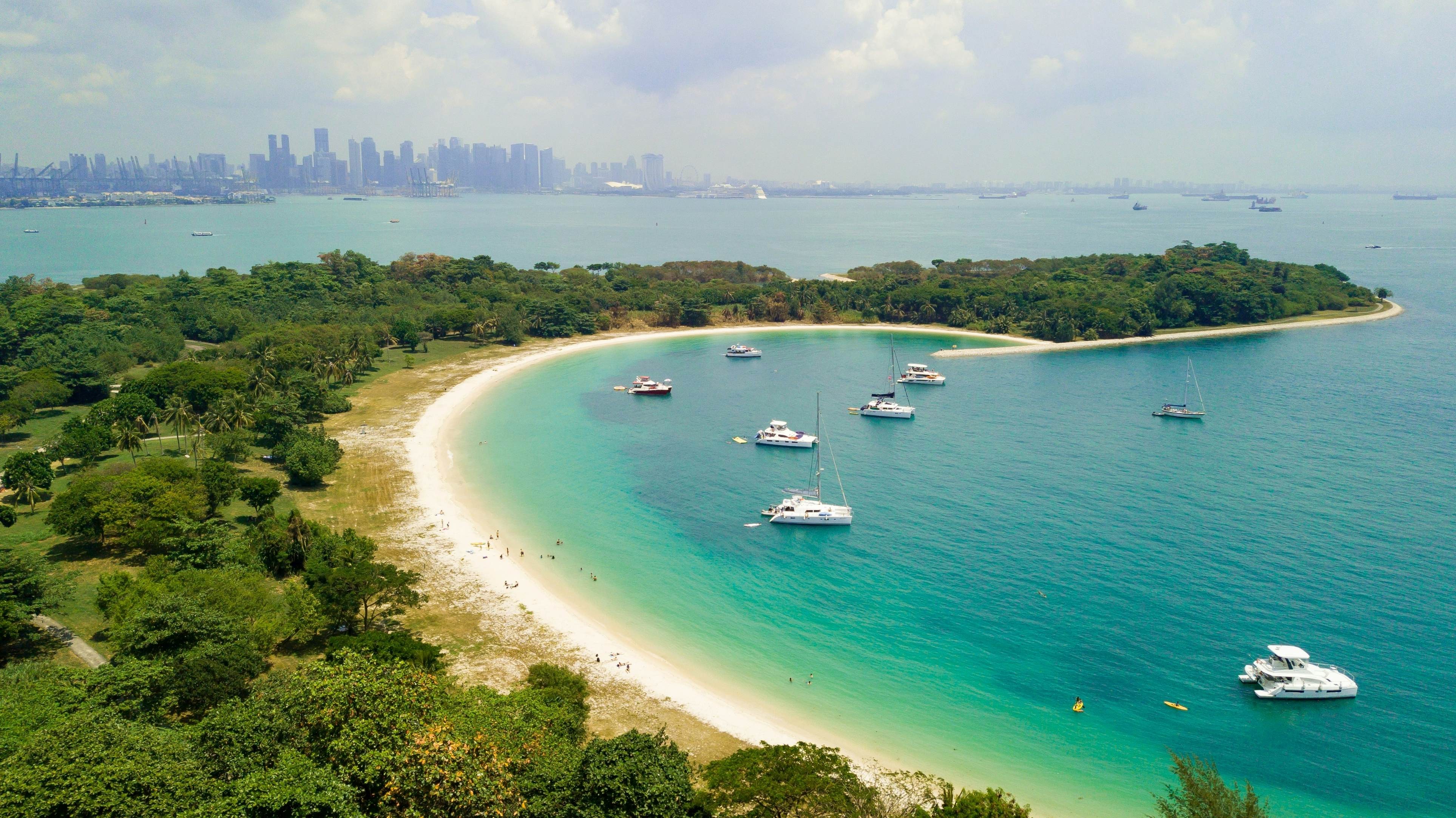 A scenic view of Lazarus Island beach in Singapore with boats and city skyline in the distance