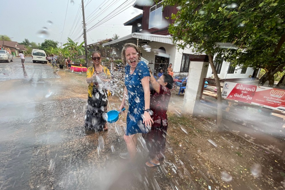 Editor Brook being playfully splashed with water by locals during the Songkran Water Festival in Laos, capturing the joyful and festive atmosphere of the Lao New Year celebrations