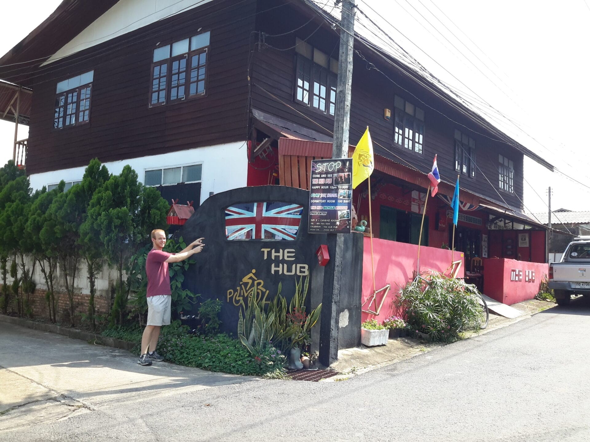 A person standing in front of The Hub Pub in Chiang Khong, Thailand, pointing at the establishment