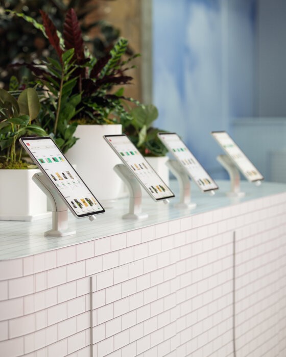 Customers using iPads to browse products inside The Travel Agency dispensary, with budtenders available for assistance.