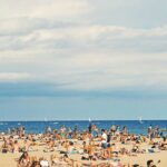 A beach crowded with locals and travelers on a partly cloudy day