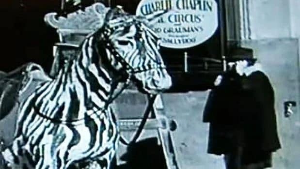 A still photograph from behind the scenes of a Charlie Chaplin film, showing a woman holding an object to her ear resembling a cell phone, sparking debate about time travel.