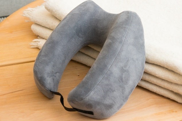 Travelrest Ultimate memory foam neck pillow in donut shape, resting on a blanket, Wirecutter's top pick for travel pillows.