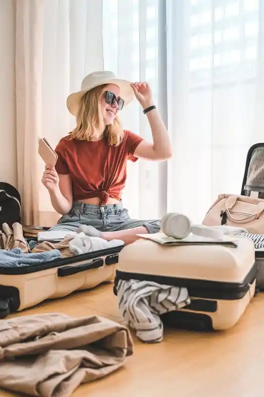 Girl packing suitcase for travel booked on best travel booking websites. Planning a staycation or vacation with online travel agencies.