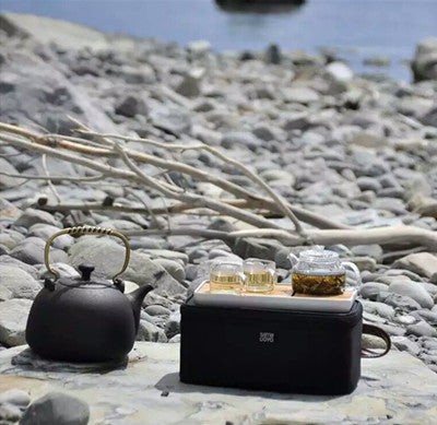 A person enjoying tea from a travel tea set outdoors, highlighting the lifestyle and freedom it offers to tea lovers.