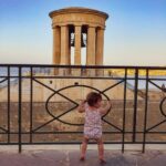 traveling baby standing in front of impressive bell tower