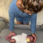 Woman gently placing newborn in a portable travel bassinet