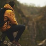 Finding personal meaning: A hiker pauses to reflect on their travel experiences in a breathtaking mountain setting.