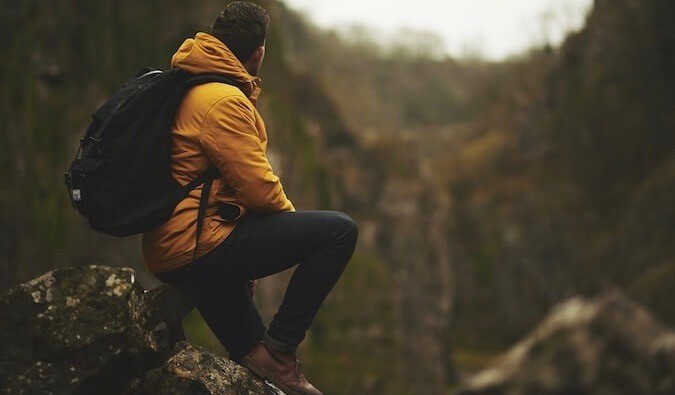 Finding personal meaning: A hiker pauses to reflect on their travel experiences in a breathtaking mountain setting.