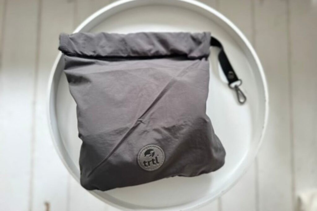 The Trtl Pillow neatly packed inside its travel case, which can be clipped onto luggage for easy transport.