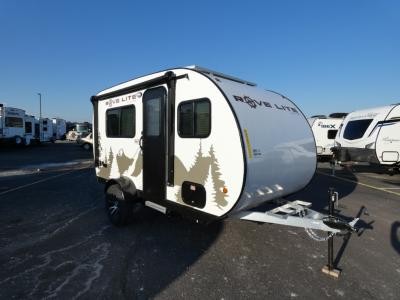 A family standing in front of their used travel trailer at a campsite, smiling.