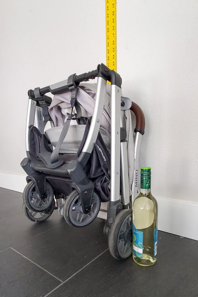 folded uppababy minu with wine bottle for size reference, about half as tall as the minu