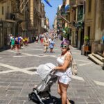 woman pushing uppababy minu stroller through crowded street in valletta malta