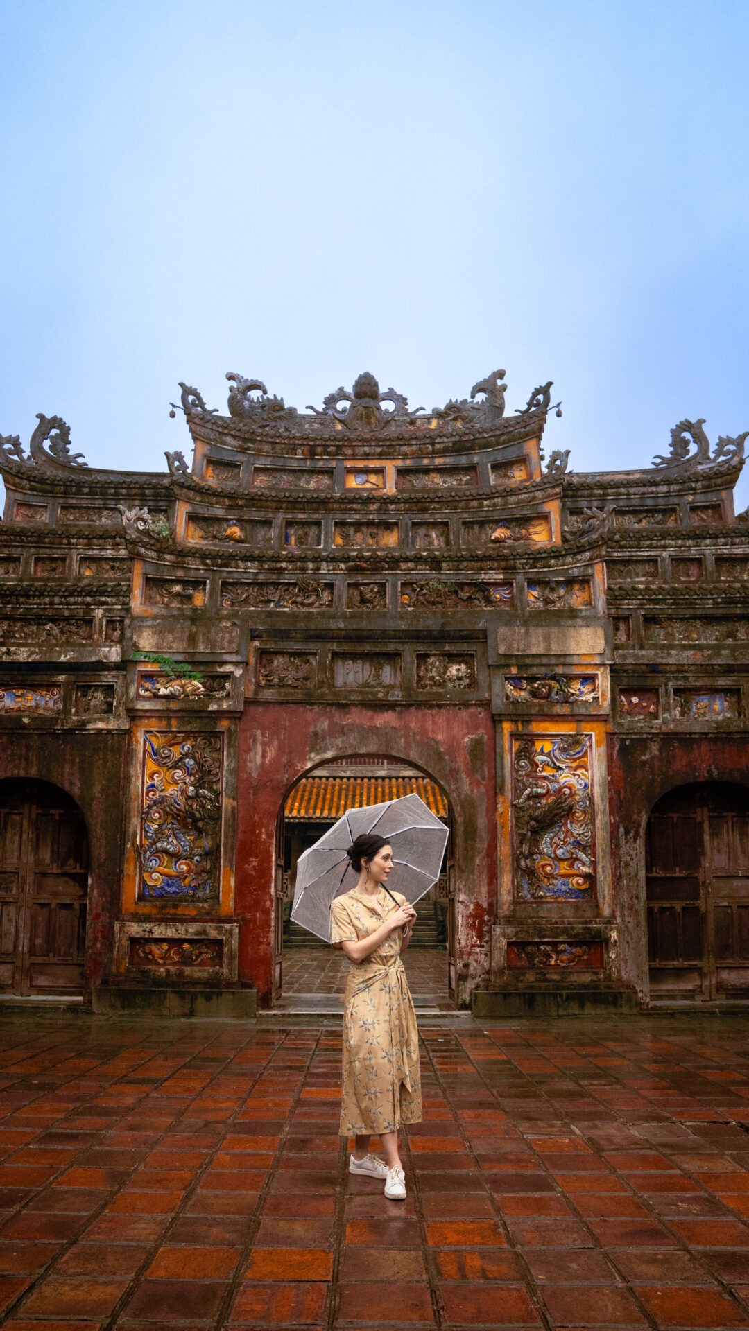 Travel blogger Jordan Gassner holding an umbrella in the rain at the Imperial Citadel of Hue, Vietnam, experiencing the wet weather conditions - Vietnam travel blog 2024