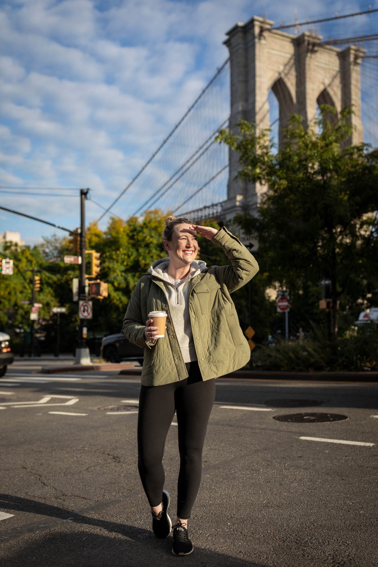 Woman wearing a navy blue Vuori athleisure set with a zip-up jacket and leggings, standing outdoors with a neutral-toned backpack, showcasing a sporty and comfortable travel outfit