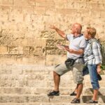 Happy senior couple exploring old town of la Valletta with city map.