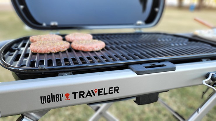 Weber Traveler grill with burger patties cooking on the grill grates